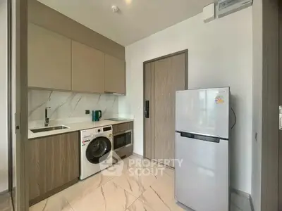 Modern kitchen with washing machine and fridge in sleek apartment