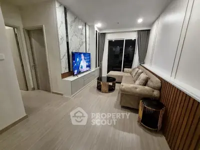 Modern living room with stylish decor and large TV, featuring a cozy sofa and elegant wall design.