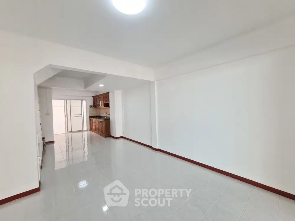 Spacious open-plan living area with tiled flooring and modern kitchen.