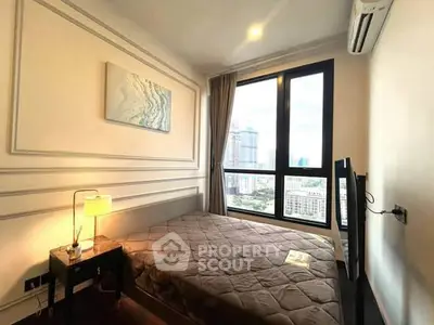 Cozy bedroom with city view, featuring modern decor and natural light through large windows.