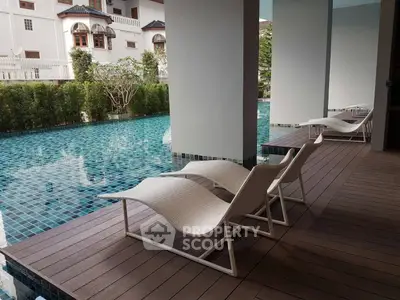 Luxurious poolside area with stylish lounge chairs and serene water view.