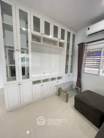 Modern living room with built-in white cabinets and glass table
