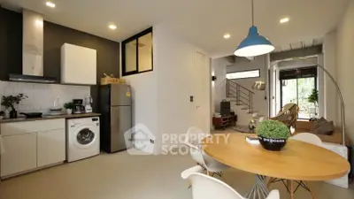 Modern open-plan living space with a sleek kitchen, dining area, and cozy lounge, featuring a washing machine and ample natural light.