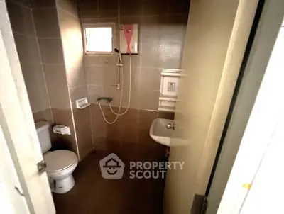 Compact bathroom with shower, toilet, and sink in a cozy real estate unit.