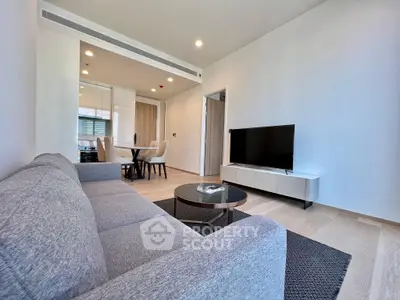 Modern living room with sleek furniture and open layout, featuring a cozy sofa and flat-screen TV.