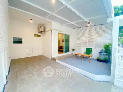 Modern covered patio with seating area and plants, perfect for relaxation and outdoor gatherings.
