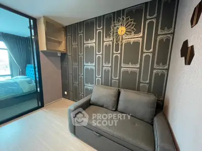 Modern living room with stylish wallpaper and cozy sofa, adjacent to a bedroom with elegant decor.