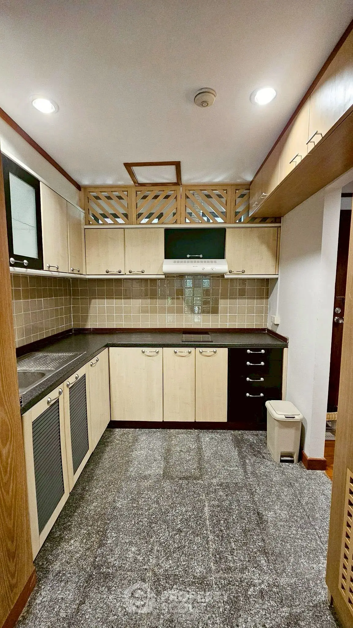 Spacious kitchen with modern cabinetry and tiled backsplash in a cozy apartment.