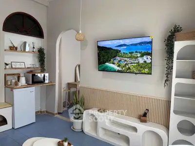 Charming living room with modern decor, wall-mounted TV, and cozy kitchenette in stylish apartment.