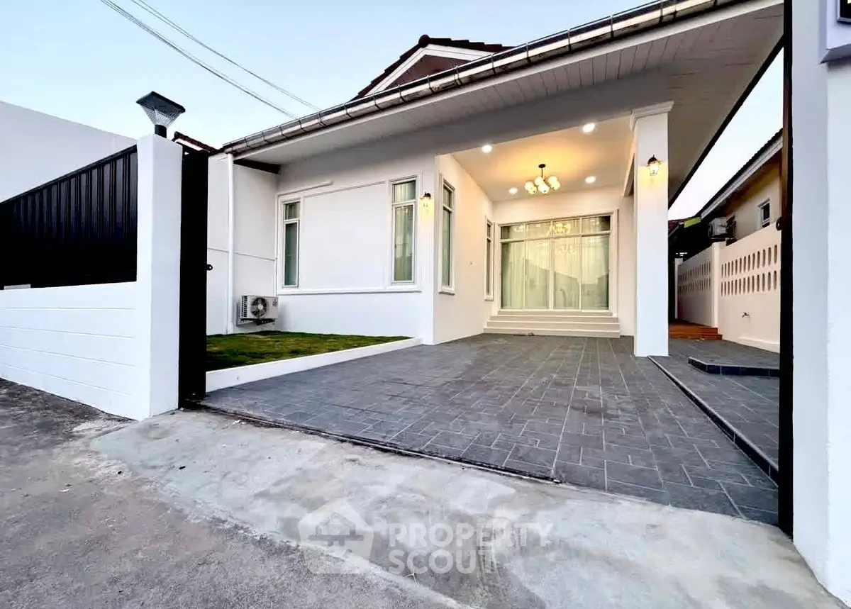 Modern single-story home with spacious driveway and elegant entrance lighting.