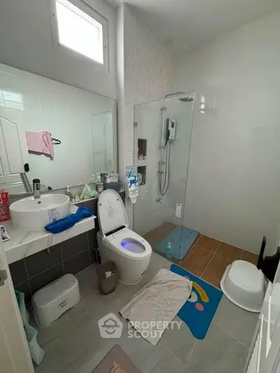 Modern bathroom with glass shower, stylish sink, and bright natural light.