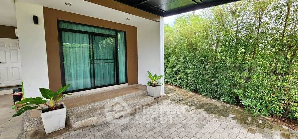 Charming home entrance with lush greenery and modern design.