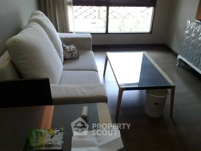 Cozy living room with modern sofa and glass coffee table, perfect for relaxation.