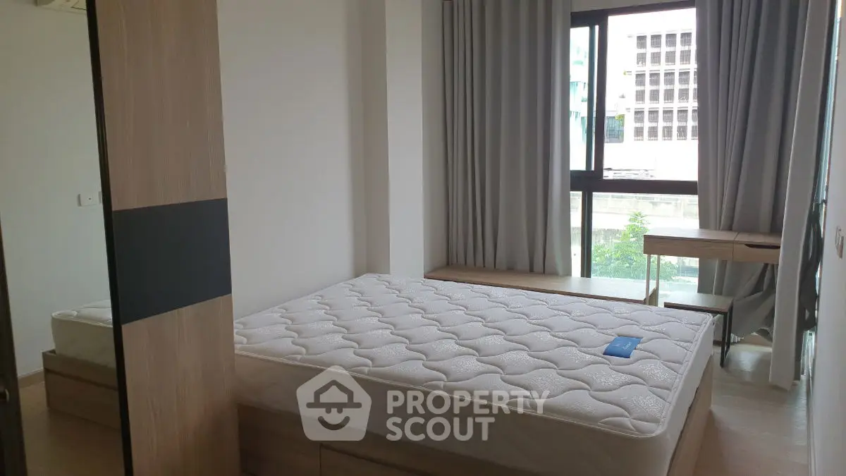 Modern bedroom with large window and natural light, featuring a comfortable bed and stylish furnishings.