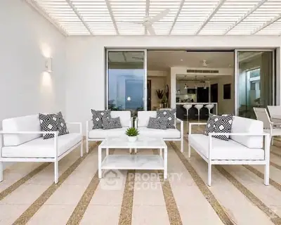 Luxurious modern patio with stylish white furniture and open access to elegant interior kitchen.
