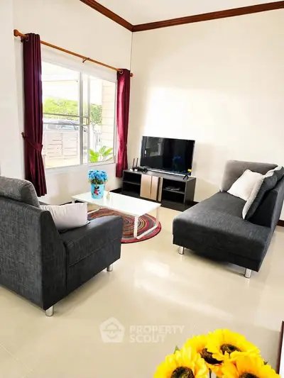 Charming living room with modern gray sofas, TV setup, and vibrant decor, perfect for cozy family gatherings.