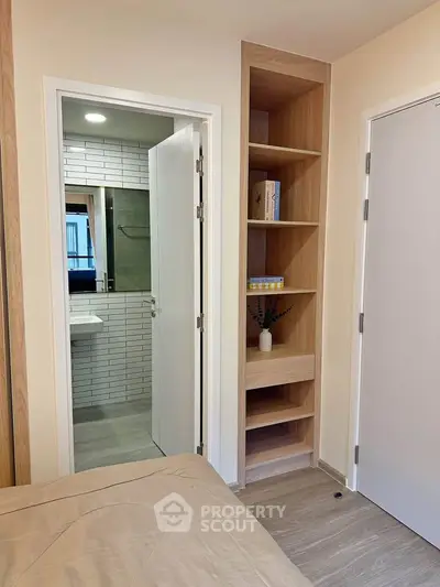Modern bedroom with built-in shelves and en-suite bathroom featuring sleek design.