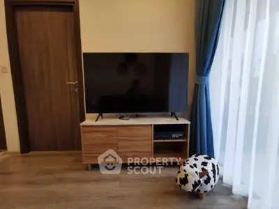 Modern living room with stylish TV stand and large flat-screen TV, complemented by elegant curtains and wooden flooring.