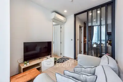 Modern living room with sleek design, featuring a cozy sofa, flat-screen TV, and stylish partition leading to kitchen.