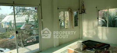 Bright room with large windows and sliding glass door overlooking garden area.