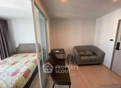 Modern apartment interior with cozy living area and bedroom separated by glass doors.