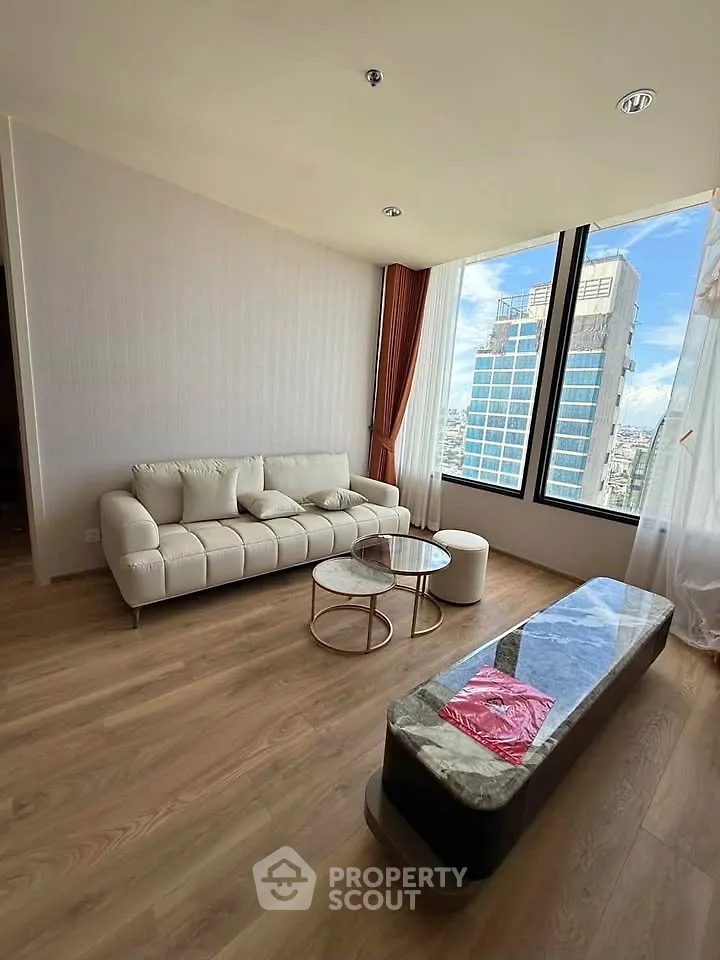 Spacious living room with modern furniture and city view, featuring large windows and elegant decor.