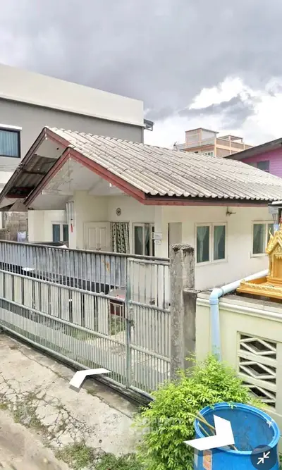 Charming single-story house with gated entrance and sloped roof in a suburban neighborhood.