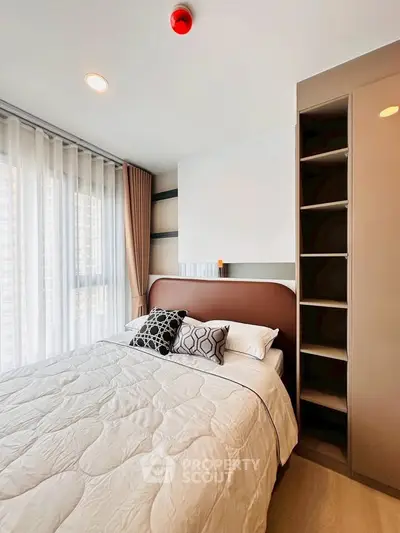 Modern bedroom with stylish decor and ample natural light, featuring a cozy bed and built-in storage.