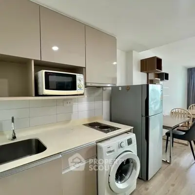 Modern kitchen with washing machine, microwave, and dining area in open layout apartment.