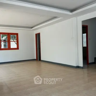 Spacious empty room with tiled floor and red window frames