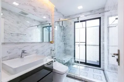 Luxurious modern bathroom with marble walls and glass shower enclosure