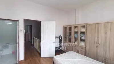Spacious bedroom with wooden flooring and ample storage space.