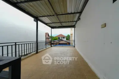 Spacious covered balcony with tiled flooring and scenic view of surrounding houses.