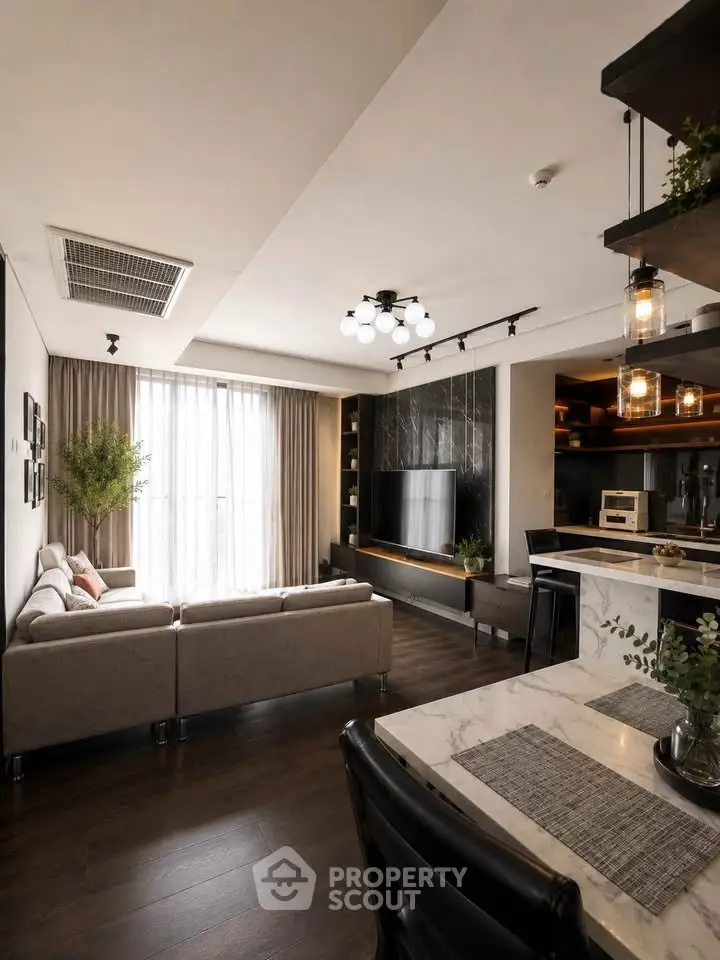 Modern living room with stylish decor and open kitchen layout, featuring a cozy sofa and large TV.