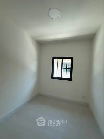Minimalist small room with window and white walls, perfect for a cozy study or storage space.