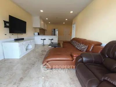 Spacious living room with modern leather sofa and open kitchen layout, perfect for entertaining.