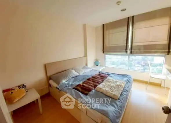 Cozy bedroom with large window offering city view and natural light.