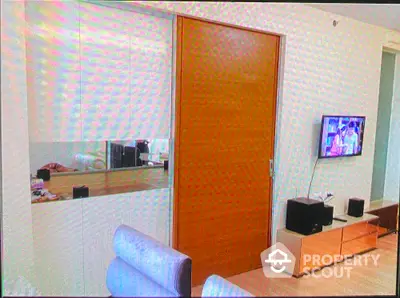 Modern living room with sleek wooden door and wall-mounted TV