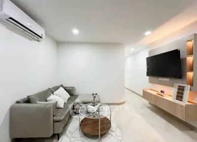 Modern living room with sleek furniture and wall-mounted TV, perfect for relaxation and entertainment.