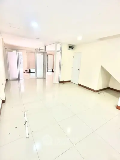 Spacious empty room with glossy tiled floors and bright natural light, ideal for customization.