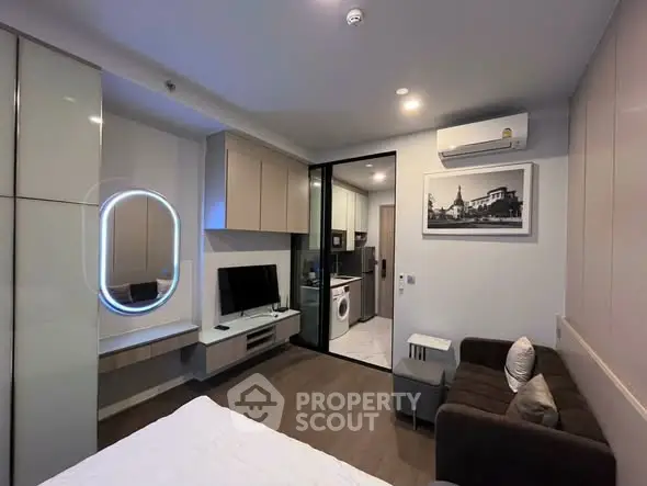 Modern studio apartment with sleek design, featuring a cozy living area, wall-mounted TV, and compact kitchen.