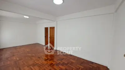 Spacious empty room with polished wooden floors and white walls, ideal for customization.