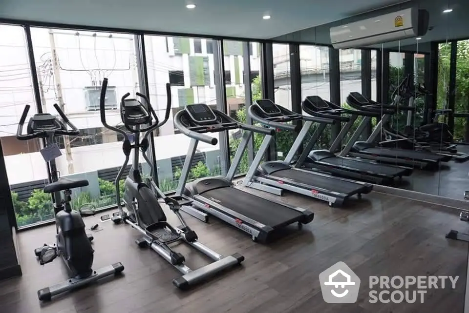 Modern gym with treadmills and exercise bikes in a glass-walled fitness room.