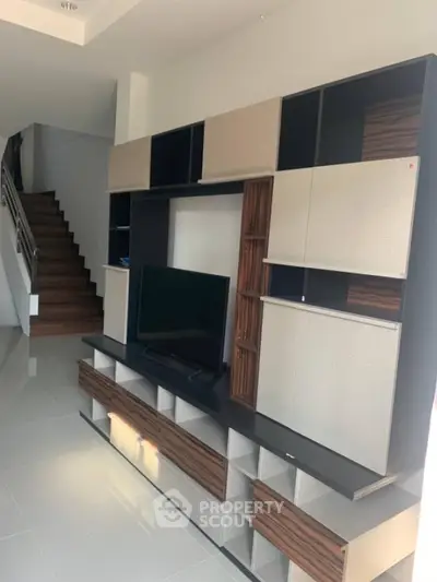 Modern living room with stylish entertainment unit and sleek staircase