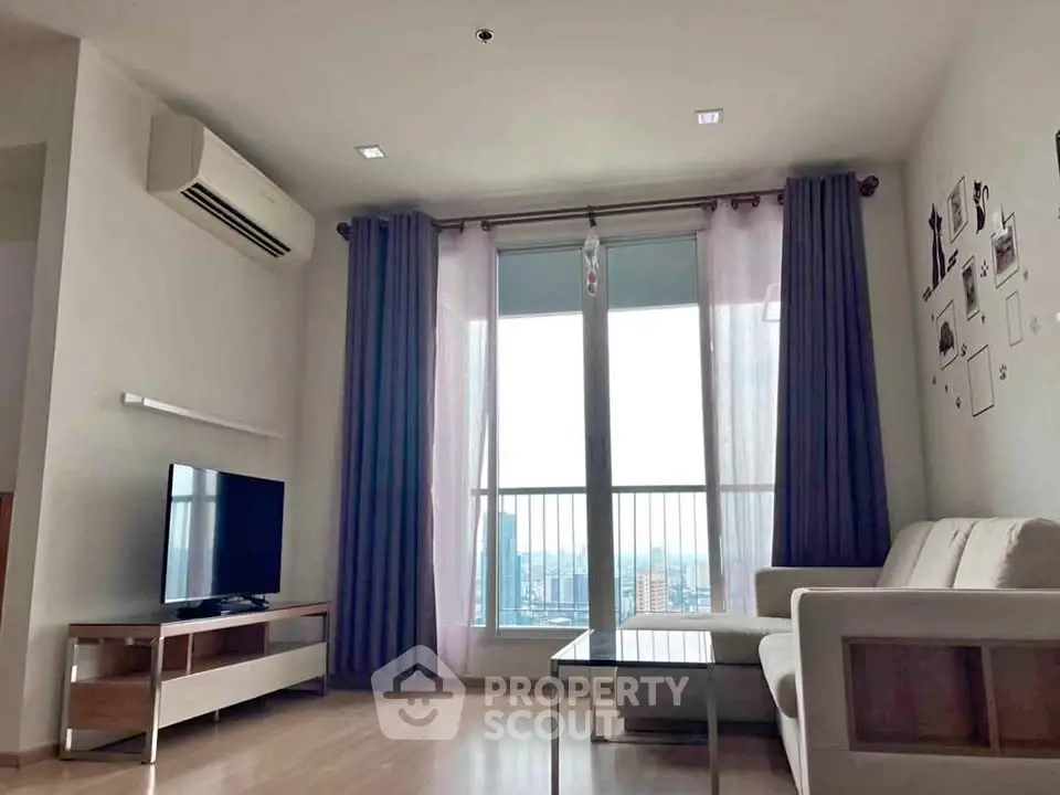 Modern living room with large windows and city view, featuring a cozy sofa and entertainment unit.