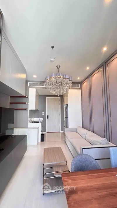 Luxurious modern living room with elegant chandelier and sleek furniture in a high-end apartment.