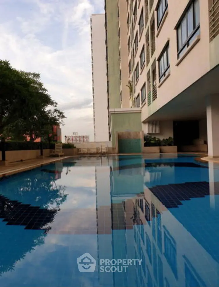 Luxurious apartment building with a stunning outdoor pool reflecting the sky, perfect for relaxation.