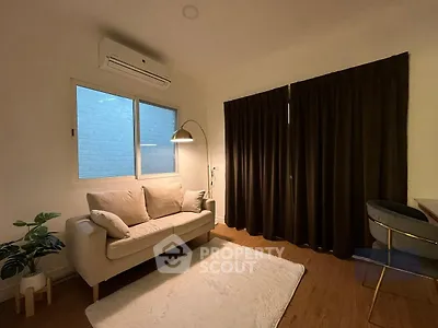 Cozy living room with sofa, floor lamp, and air conditioning unit.