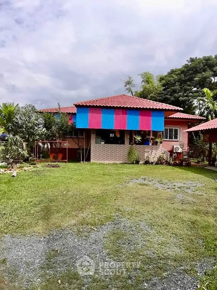 Charming single-story home with vibrant awning and lush garden, perfect for tranquil living.