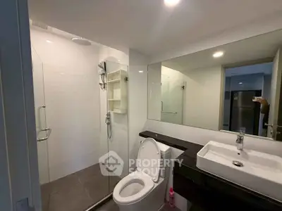 Modern bathroom with glass shower and sleek fixtures in contemporary apartment.